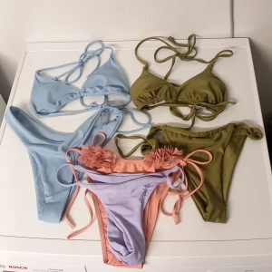 6 delar bikinis rosa lila blå grön Stl S/ Xs - 6 snygga bikini-delar: ljusblå ribbad med knyt, olivgrön med snörning, samt en lila och persikofärgad bikini med blommiga detaljer och knyt i sidorna. Perfekta för stranden eller poolen, trendiga färger och feminina former. Köparen betalar frakten.