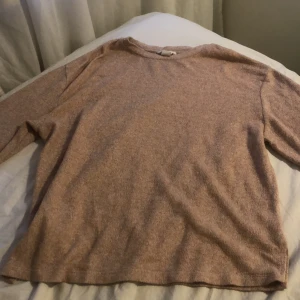 Beige/rosa stickad tröja från H&M - Mysig beige stickad tröja från H&M i storlek S. Tröjan har en enkel och avslappnad passform med rund halsringning och långa ärmar. Perfekt för lager-på-lager under kyliga dagar.