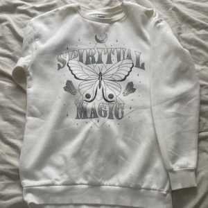 Vit sweatshirt Spiritual Magic Kappahl - Vit sweatshirt från Kappahl med tryck i grått och svart framtill. Motiv med fjäril, kristaller och texten 'Spiritual Magic'. Rund halsringning och långa ärmar. Mjuk insida och ribbade muddar vid ärmslut och nederkant. aldrig använd!!