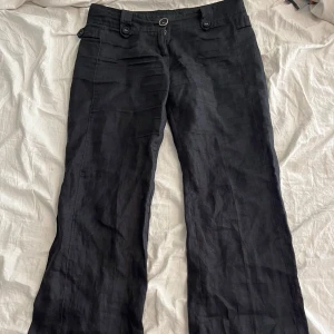 Svarta linnebyxor från French Connection - Svarta linnebyxor från French Connection med snygg bootcut-passform. Byxorna har låg midja, knappar vid linningen och är tillverkade i ett luftigt linnematerial. Perfekta för dig som gillar en stilren och avslappnad look.Pris kan diskuteras,knappen har sytts dit en gång och sitter lite löst men annars inge problem. Skriv om mer bilder för får inte upp hela bilden här på Plick så skriv privat om ni vill ha synligare bilder 