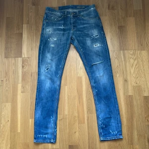  Blå slitna Dondup jeans med slitningar W30 L32 - Säljer ett par blå jeans med slitningar och trasiga detaljer framtill. Jeansen har klassisk femficksdesign, raka ben och normal passform. Perfekta för dig som gillar en avslappnad och trendig streetstil.