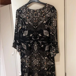 Klänning - Odd Molly - Svart klänning från Odd Molly med unikt blommigt och grafiskt mönster i beige, grått och ljusrosa. Modellen har trekvartsärm och avslappnad passform. Perfekt för dig som gillar boho-vibe och snygga detaljer. Storlek 1 = 38 (?) 🖤
