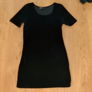 Svart sammetsklänning från Cubus stl. S - En svart sammetsklänning från Cubus i kort modell. Klänningen har rund halsringning och korta ärmar, med en figurnära passform. Endast använd 1 gång