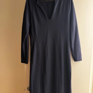 Mörkblå klänning från Filippa K - Snygg mörkblå klänning från Filippa K med v-ringning och trekvartsärm. Enkel och stilren design i mjukt material, perfekt för dig som gillar minimalistisk stil. Klänningen har en rak passform och är knälång. Är mer som en M i storleken. Använd en gång. 