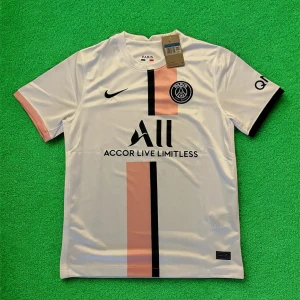 PSG vit matchtröja Nike 2021/22 - Paris Saint-Germain fotbollströja i vitt med rosa och svart vertikal rand på framsidan. Tröjan har korta ärmar, rund hals och PSG-logga på bröstet. Tillverkad i lätt och ventilerande polyester, perfekt för träning eller match. Snygg detalj med svarta och rosa ärmslut.