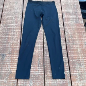 Svarta leggings från SOC - Svarta leggings från SOC med elastisk midja och diskret logga vid benet. Tight passform och tillverkade i stretchigt syntetmaterial som passar perfekt för träning eller chill. Snygg och enkel design som funkar till det mesta.