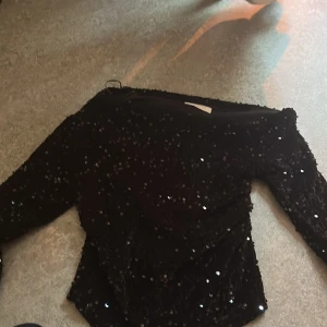 Svart paljettopp från Rut&Circle XS - Säljer en svart långärmad topp från Rut&Circle i storlek XS. Hela toppen är täckt av glittriga paljetter som ger en riktigt snygg och festlig look. Modellen är figurnära och har en klassisk rund halsringning. Perfekt för dig som vill sticka ut. Använd 1 gång!❤️ köpt för 500kr