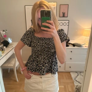 Svart blommig blus - Supersöt svart blus med vita blommor . Smockad över bysten 💕💕 