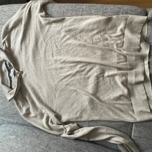 Beige half zip-tröja från Jack & Jones - Snygg beige långärmad tröja från Jack & Jones med half zip-dragkedja vid halsen. Tröjan är i mjuk bomull och har ribbade muddar vid ärmslut och nederkant. Perfekt för lager-på-lager och chill vardagsstil.