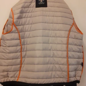 Svart dunjacka från Rema Performance - Svarta jackor med dragkedja framtill och orange detaljer. Jackor har två fickor med dragkedja fram och en logotyp på bröstet. Insidan är ljusgrå med orange kantband. Svarta dunjackor från Rema Performance i storlekar L och XL. Jackor har orange detaljer, broderad logga på bröstet och randiga dragkedjor. Insidan är ljusgrå med orange kantband. Perfekt för kalla dagar och riktigt snygg med sin quiltade look. JACKOR ÄR HELT NYA OCH OANVÄNDA