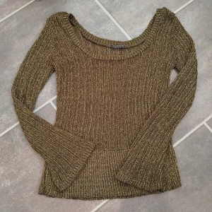 Guldig ribbad tröja Sisters Point - Supersnygg ribbstickad tröja från Sisters Point i guldigt garn. Tröjan har lång ärm, rund halsringning och glittrig finish som verkligen sticker ut. Perfekt för dig som vill ha något extra till outfiten. Sitter tajt och har stretchigt material.