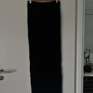 Svart ribbad långkjol Gina Tricot XS - Svart långkjol från Gina Tricot i ribbat material. Kjolen har en tight passform och är hög i midjan, perfekt för en clean och stilren look. Enkel att matcha med både sneakers och boots.