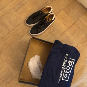 Svarta sneakers från Polo Ralph Lauren - Stilrena svarta sneakers från Polo Ralph Lauren med vit sula och vit detalj på. Skorna är nästan helt nya, har använt dom max 2 gånger, skriv vid minsta fundering!
