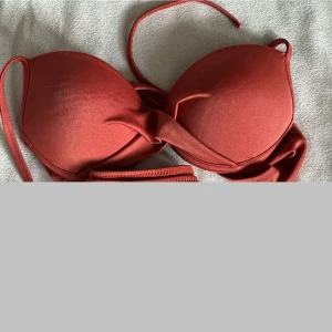 Rostfärgad / Bronze bikinitopp / överdel - Säljer en snygg rostfärgad bikinitopp med vadderade kupor och knytdetalj framtill. Använd men är i mycket fint skick.                     Tyvärr är alla etiketter bortklippta men jag är nästan säker på att den är från NA-KD. Kan skicka fler bilder vid önskemål 🤗