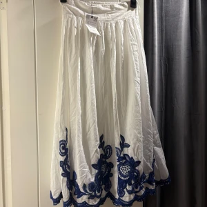 Vit långkjol med blå broderi XS - Superfin vit långkjol med blå broderade detaljer längst ner! 