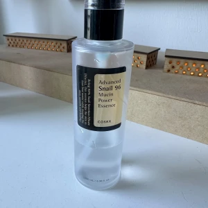 COSRX Snail 96 Mucin Essence - COSRX Advanced Snail 96 Mucin Power Essence i genomskinlig plastflaska med svart pump. Innehåller 100 ml essence med snigelsekret, perfekt för återfuktning och glow. Lätt, genomskinlig formula som absorberas snabbt av huden. Mängd kvar syns på bild 2