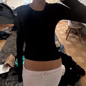 Svart långärmad tight tröja - En svart långärmad tröja med tight passform och rund halsringning. Enkel och stilren design som sitter figurnära och passar perfekt till jeans eller kjol. Materialet känns mjukt och stretchigt, vilket gör den bekväm att bära hela dagen.