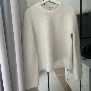 mohair tröja - Mysig vit stickad tröja med rund hals och långa ärmar. Tröjan har en fluffig och mjuk känsla, perfekt för kyligare dagar. Enkel och stilren design som passar till många olika outfits.