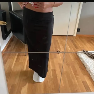 Svart långkjol från 157 - Säljer en svart långkjol från 157 i enkel och stilren design. Kjolen har en rak passform och en slits bak för extra rörelsefrihet. Perfekt att styla med crop top eller stickad tröja. Kjolen är i ett mjukt och stretchigt material.