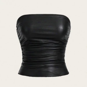 Svart tubtopp - Säljer en svart tubtopp i glansigt skinnliknande material. Toppen är axelbandslös och har rynkade detaljer längs sidorna för en snygg passform. 