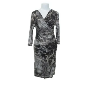 Mönstrad omlottklänning från Simplicity New York - Elegant fodralklänning från kvalitetsmärket Simplicity New York med ormmönster i svart, vitt och grått. Italiensktillverkad i mjuk viskosblandning med stretch, omlottringning och draperad midja som smickrar figuren. Perfekt för både vardag och fest. Använd sparsamt – mycket fint skick. Prutning ej möjlig, men bundlerabatt ges. Passa på! Jag rensar garderoben – kika gärna på mina andra annonser också. 