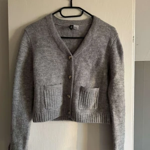 Grå kofta med fickor och knappar - Mysig grå kofta från hm med v-ringning, ribbade muddar och två framfickor. Storlek XXS men känns som en S