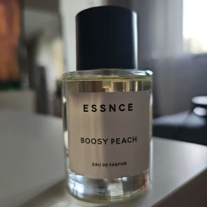 Boosy Peach EDP från Essnce 50ml - Nästan helt oanvänd. Luktar som den dyyyra Tom Ford Bitter Peach extremt mycket! Boosy Peach från Essnce är en unisexparfym med doftnoter av persika, rom, konjak, patchouli, vetiver, vanilj och kashmirträ. Flaskan är genomskinlig med svart lock och vit etikett. Doften är fruktig, träig och pudrig med inslag av sötma och kryddighet.