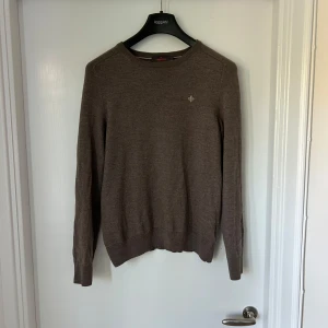 Brun merinoullströja från Morris - Säljer en klassisk brun stickad tröja från Morris i 100% merinoull. Tröjan har rund halsringning, diskret logga på bröstet och ribbade muddar vid ärmslut och nederkant. Perfekt för en stilren och bekväm look. Det är en storlek M men den passar som en S. nypris 1500kr!