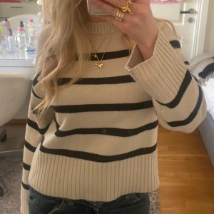 Beige och svart randig stickad tröja - Tröjan har rund halsringning, långa ärmar och bred ribbad mudd vid ärmslut och nederkant