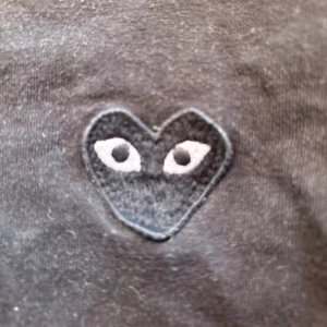 Svart långärmad tröja från Comme des Garçons Play - Svart långärmad tröja från Comme des Garçons Play med det ikoniska hjärta med ögon broderat på bröstet. Tröjan har rund halsringning och är tillverkad i mjuk bomull. Perfekt för en stilren och enkel look.