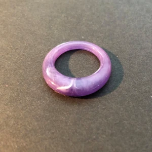 Lila ring i akryl - Säljer en chunky lila ring i akryl med marmorerad effekt. Ringen har en rundad form och är helt slät utan detaljer. Den väger ingenting så den är inte jobbig att ha på sig. Ringen har diameter 1,7 cm. Perfekt för dig som vill ha en färgklick till din outfit!