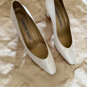 Vita pumps från Martinez Valero - Säljer ett par klassiska vita pumps från Martinez Valero med rund tå och klack. Skorna är i skinn och har en elegant, tidlös design som passar perfekt till många olika tillfällen.