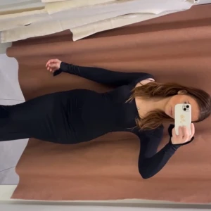 Svart långärmad långklänning - Säljer en elegant svart långklänning med lång ärm och figurnära passform. Klänningen har en stilren design och är perfekt för dig som gillar en minimalistisk look. Passar utmärkt till festliga tillfällen eller när du vill känna dig extra snygg.