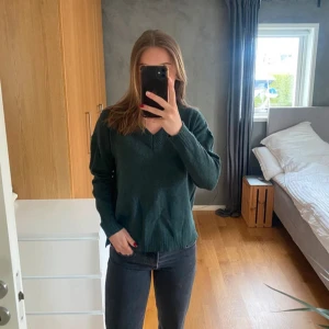 Mörkgrön stickad tröja med v-ringning från Vila - Mysig mörkgrön stickad tröja från Vila med v-ringad hals och ribbade muddar. Super skön i materialet och inte sticksig alls. Aldrig använd pga inte min färg :). Storlek S.  Nypris 799kr