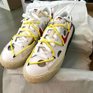 Nike x Off-White Blazer Low sneakers med gula snören - Säljer ett par Nike x Off-White Blazer Low sneakers i vitt med röda och blå detaljer samt unika gula snören. Skorna har Off-White-etikett och text på sidan, samt en chunky beige sula med svarta och gula inslag. Str42.5