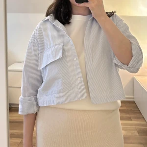 Blåvit randig skjorta från Zara - Säljer en croppad skjorta från Zaras barnavdelning i blåvitt randigt bomullstyg. Skjortan har klassisk krage, en stor bröstficka och knappar framtill. 