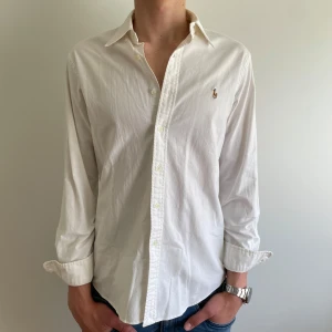 Vit skjorta från Ralph Lauren - Säljer en vit skjorta från Ralph Lauren i storlek L. Skjortan har en slim fit passform och perfekt inför sommaren! 🏖️Den är i mycket bra skick och om du har frågor eller funderingar så tveka inte på att skriva! 🤩