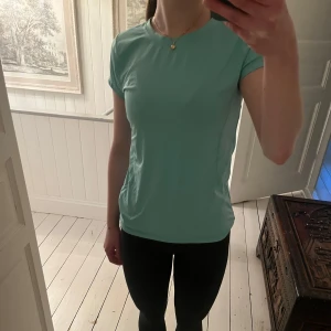 Tränings t-shirt från SOC - Säljer en mint/turkos tränings t-shirt från SOV med rund halsringning och korta ärmar. Perfekt för träning eller sportiga dagar. Materialet är lätt och andas, vilket gör den bekväm att bära under aktivitet. Storlek 158/164, men passar mig som har S. Använd nån enstaka gång men utan defekter. Lite svårt att fånga färgen på bild.