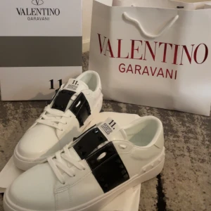 Valentino Garavani Rockstud Untitled sneakers - Snygga vita sneakers från Valentino Garavani med svarta detaljer och ikoniska nitar på sidan. Skorna har rund tå, platt sula och snörning. Perfekta för dig som gillar exklusiv och modern stil.