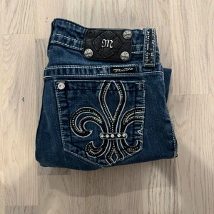 Miss Me Jeans Boot W27 - Snygga blå jeansbyxor från Miss Me med dekorativa broderier och nitar på bakfickorna. Byxorna har tydliga kontrastsömmar, silverfärgade knappar och detaljer samt normal passform. Perfekta för dig som vill sticka ut med coola detaljer. Jeansen är i w27 och bootcut :) följare får lite rea
