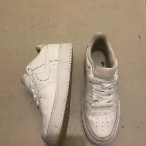 Vita Nike Air Force 1 sneakers - Klassiska helvita Nike Air Force 1 sneakers med rund tå och snörning. Skorna har en platt sula och är tillverkade i syntetmaterial med diskret Nike-logga på sidan. Perfekta för en stilren och sportig look. Pris kan diskuteras .HELT NYA!!!!!
