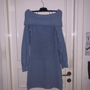 Ljusblå stickad offshoulder klänning från H&M - Mysig ljusblå stickad klänning från H&M med bred offshoulder-krage och långa ärmar. Perfekt för kyligare dagar och enkel att styla med boots eller sneakers. Mjuk och skön känsla tack vare det stickade materialet.