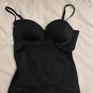 Topp - Säljer en svart tubtopp med smala axelband och lätt formad byst. Toppen är figurnära och passar perfekt till jeans eller kjol. Enkel och stilren design som är lätt att matcha.