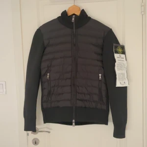 Svart jacka från Stone Island - Säljer en stilren svart jacka från Stone Island med dragkedja och långärmad design. Jackan är helt ny aldrig använd.