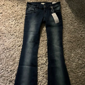 Mörkblå lowrise bootcut jeans - Snygga lowrise mörkblå bootcut jeans med klassisk femficksdesign och lätt slitna detaljer. Perfekta för en avslappnad stil med en touch av retro. Passar bra till både sneakers och klackar. Midjemått ca 37cm och Innerbenslängd ca 76-77cm.