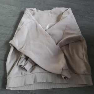 Beige sweatshirt från Gina Tricot - Säljer en beige sweatshirt från Gina Tricot med texten 'MINOT' tryckt på framsidan. Tröjan har långa ärmar och ribbade muddar vid ärmslut och nederkant. Perfekt för en avslappnad stil.