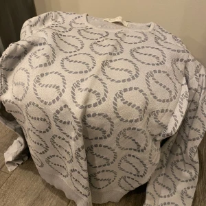 Grå mönstrad tröja från Busnel stl 36  - Säljer en stilren grå tröja från Busnel med ett unikt mönster av cirklar. Tröjan har långa ärmar och en rund halsringning. Perfekt för en elegant och avslappnad look. 🌀