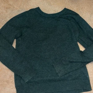 Mörkgrå tröja från VILA - Säljer en stilren mörkgrå tröja från VILA. Tröjan har långa ärmar och ribbade muddar vid ärmslut och nederkant. Perfekt för kyligare dagar.