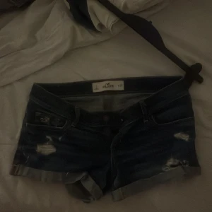 Mörkblå jeansshorts från Hollister - Säljer ett par mörkblå jeansshorts från Hollister. De har en klassisk femficksdesign och slitna detaljer för en trendig look. Perfekta för varma sommardagar!