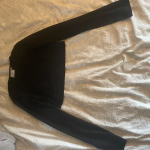 Svart croppad tröja - Säljer en stilren svart croppad tröja med långa ärmar. Perfekt för en trendig look. Passar bra till både jeans och kjol. Väldigt stretchig i materialet.